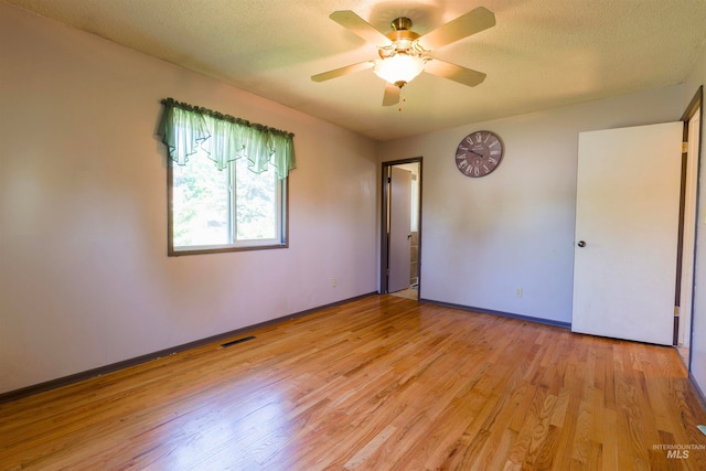 spare room with baseboards, visible vents, ceiling fan, a textured ceiling, and light wood-type flooring