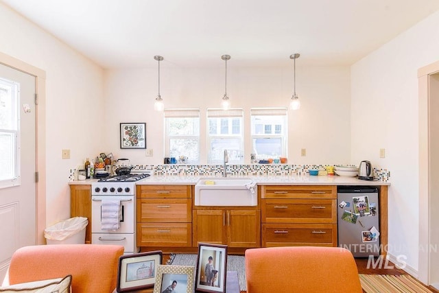 512 N Lincoln St, Moscow, ID 83843 - kitchen with a sink, white range with gas cooktop, brown cabinets, light countertops, and decorative light fixtures