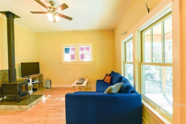 512 N Lincoln St, Moscow, ID 83843 - living room featuring a wood stove, light wood finished floors, a ceiling fan, and a healthy amount of sunlight