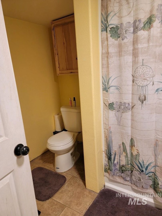 bathroom with a shower with shower curtain, tile patterned flooring, and toilet