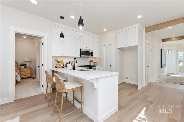 3892 W Stone House Ln, Eagle, ID 83616 - kitchen with stainless steel microwave, a peninsula, a sink, light wood-style flooring, and recessed lighting