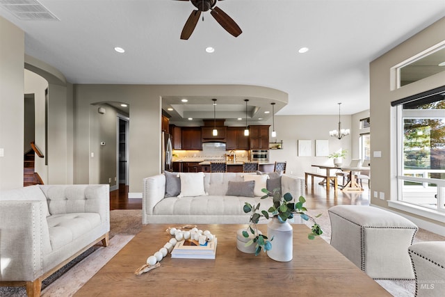 living room with light hardwood / wood-style flooring and ceiling fan with notable chandelier