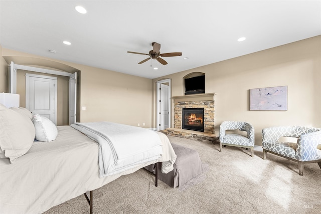 bedroom with light carpet, a fireplace, and ceiling fan