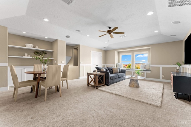 carpeted living room featuring ceiling fan, a textured ceiling, and a tray ceiling