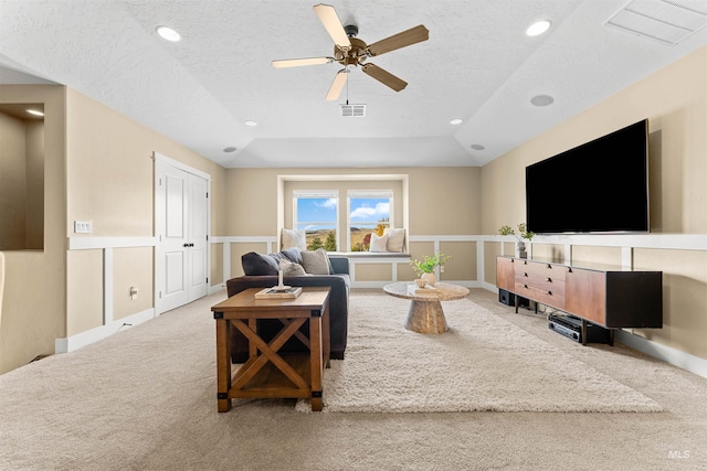 carpeted living room featuring ceiling fan, lofted ceiling, a textured ceiling, and a tray ceiling