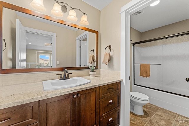 full bathroom featuring backsplash, vanity, shower / bath combination with glass door, and toilet