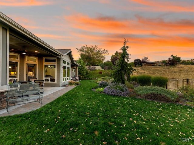 yard at dusk with a patio and ceiling fan