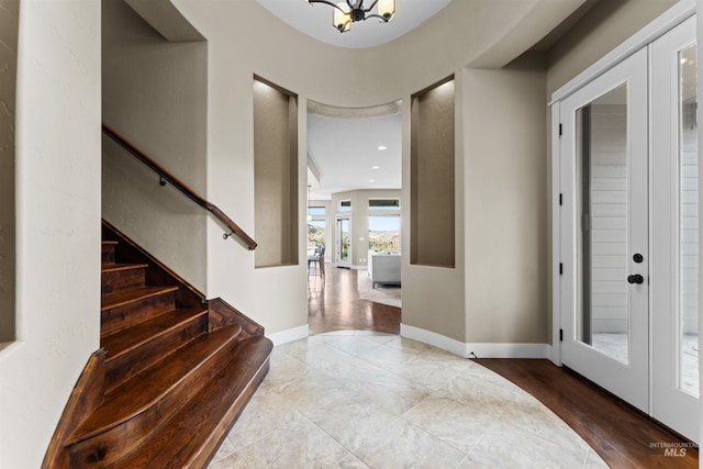 entrance foyer with a chandelier, french doors, and light wood-type flooring