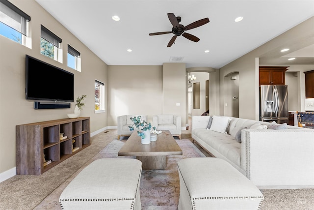 carpeted living room featuring ceiling fan with notable chandelier