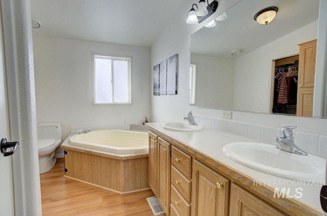 bathroom with vanity, toilet, hardwood / wood-style floors, and a tub