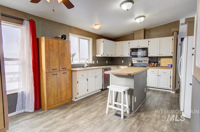 kitchen with sink, appliances with stainless steel finishes, white cabinetry, a center island, and light wood-type flooring