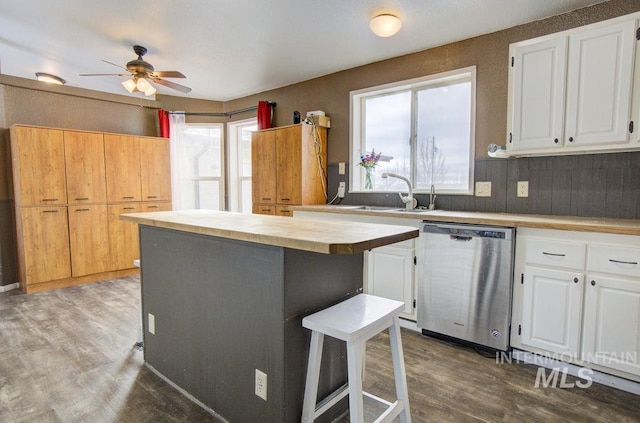 kitchen featuring sink, dishwasher, white cabinetry, a kitchen breakfast bar, and a center island