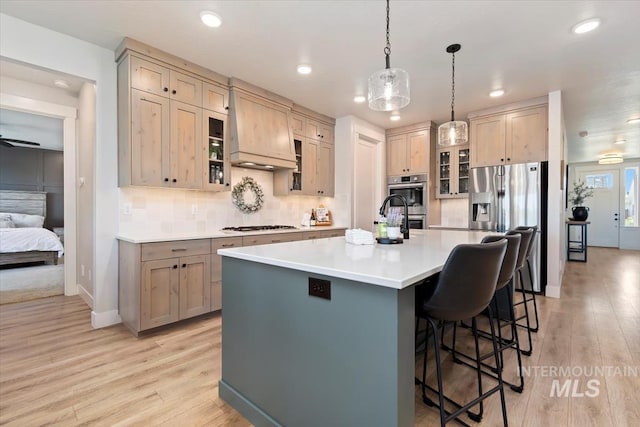 kitchen featuring light wood-style floors, appliances with stainless steel finishes, a breakfast bar, an island with sink, and recessed lighting