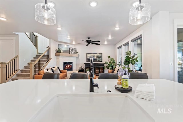 kitchen with a ceiling fan, a glass covered fireplace, decorative light fixtures, a sink, and recessed lighting