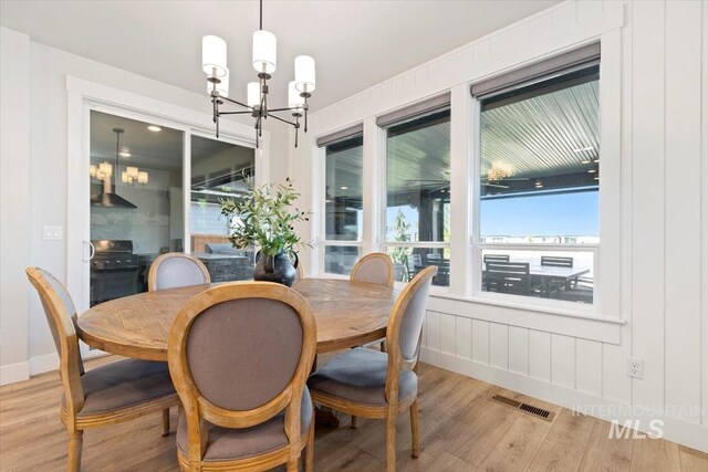 dining space with wood finished floors, a chandelier, plenty of natural light, and baseboards