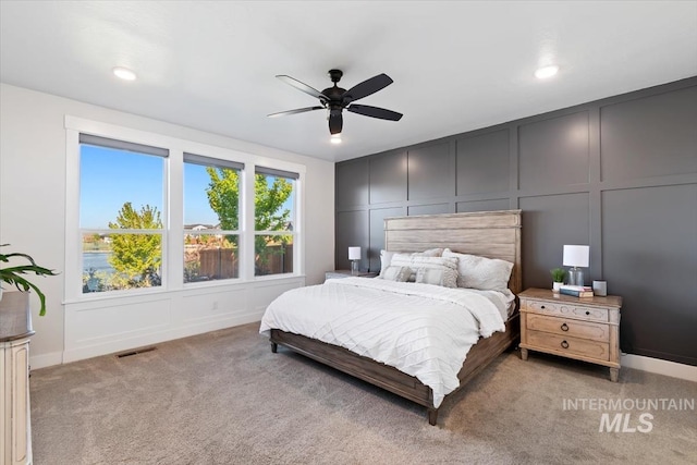 bedroom with a decorative wall, light colored carpet, a ceiling fan, recessed lighting, and baseboards