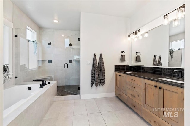 full bathroom with a bath, double vanity, tile patterned flooring, a stall shower, and baseboards