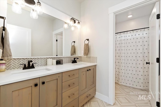 bathroom featuring backsplash, double vanity, a shower with shower curtain, and baseboards