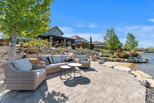 view of patio with an outdoor living space, a water view, and fence