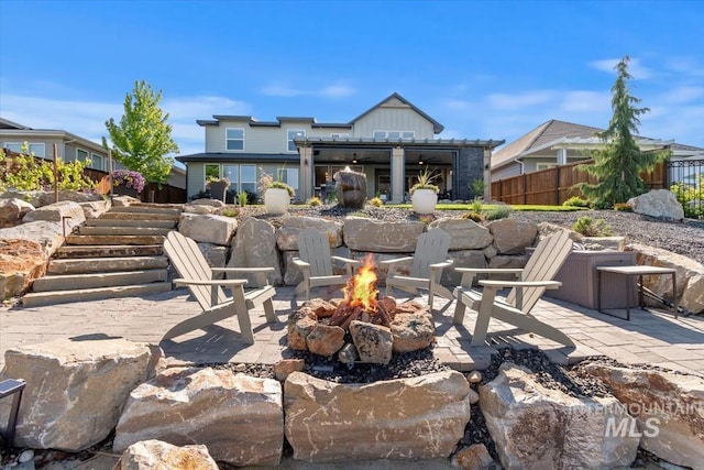 view of patio featuring an outdoor fire pit, fence, and stairs