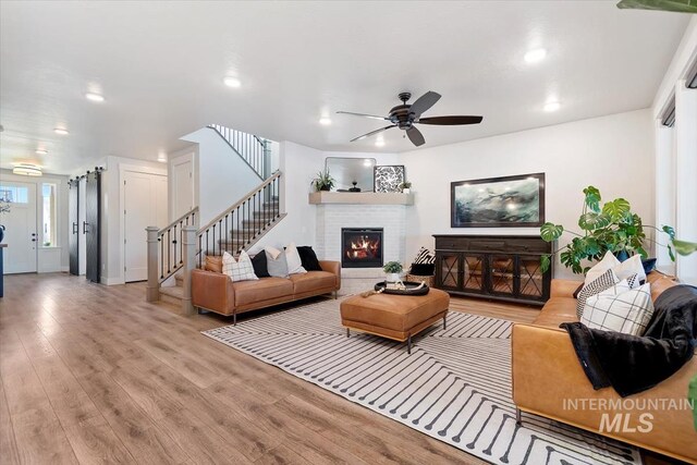 living area featuring stairway, ceiling fan, light wood-style floors, recessed lighting, and a fireplace