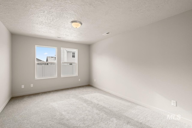 spare room featuring carpet flooring, a textured ceiling, and baseboards