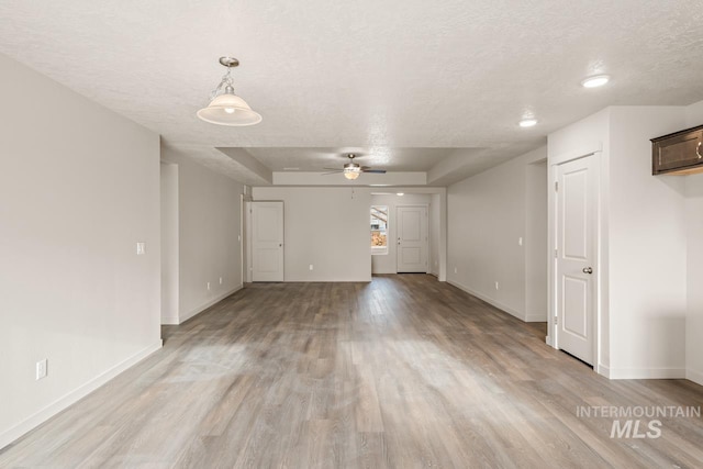 unfurnished room featuring light wood finished floors, ceiling fan, baseboards, and a textured ceiling