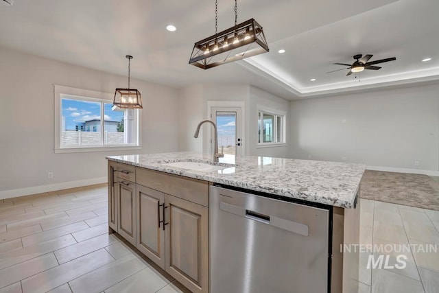 kitchen featuring a kitchen island with sink, dishwasher, a sink, and light stone countertops