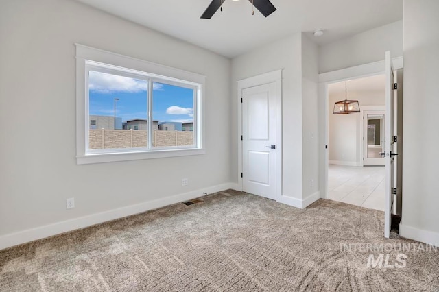 unfurnished bedroom with light carpet, ceiling fan, visible vents, and baseboards