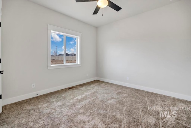 carpeted spare room with ceiling fan and baseboards