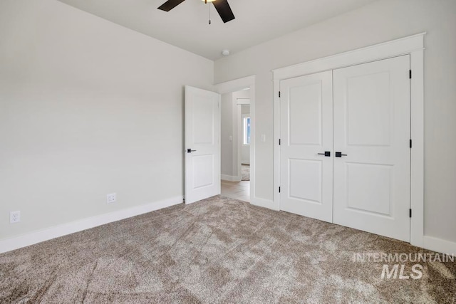 unfurnished bedroom featuring baseboards, ceiling fan, a closet, and light colored carpet