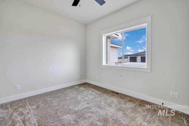 carpeted spare room featuring ceiling fan, visible vents, and baseboards