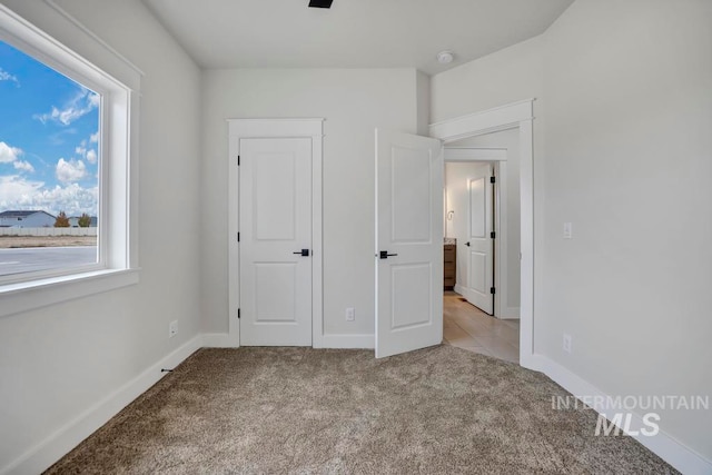 unfurnished bedroom featuring light carpet and baseboards