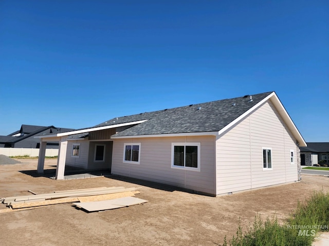 rear view of property featuring crawl space, a patio area, and a shingled roof