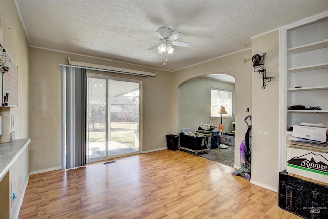 interior space with visible vents, built in shelves, ceiling fan, wood finished floors, and arched walkways