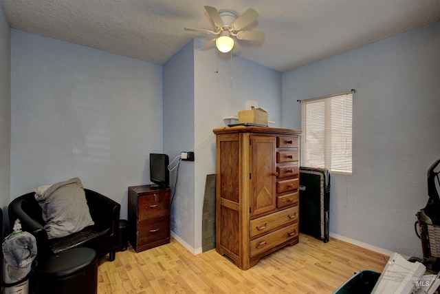 sitting room with baseboards, light wood-style floors, ceiling fan, and a textured ceiling