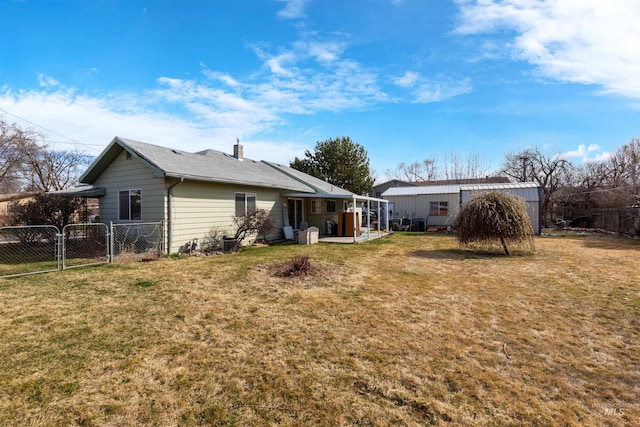 back of property with a gate, fence, a yard, and a chimney