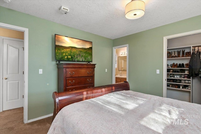 carpeted bedroom with ensuite bathroom, a textured ceiling, and a closet