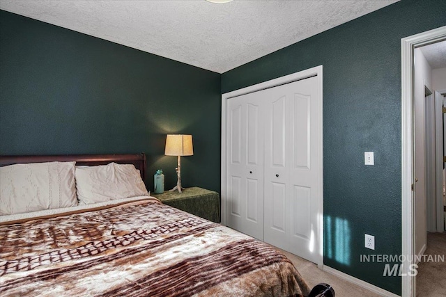 bedroom with a textured ceiling, a closet, and carpet flooring