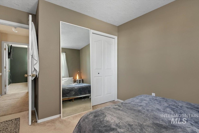 bedroom featuring a textured ceiling, light colored carpet, and a closet