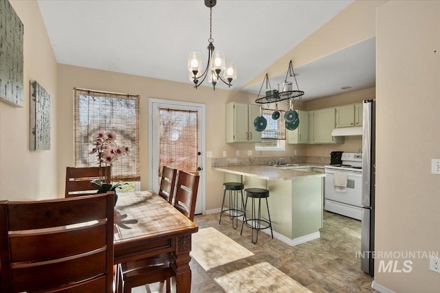 kitchen with green cabinetry, white range with electric cooktop, kitchen peninsula, a breakfast bar area, and a chandelier