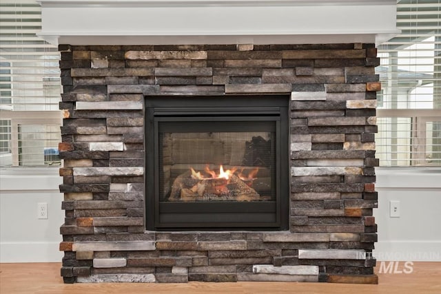 interior details with wood-type flooring and a stone fireplace