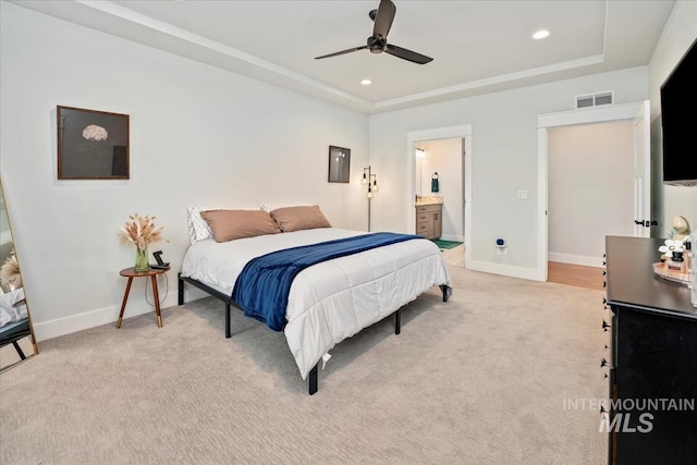 carpeted bedroom with connected bathroom, a raised ceiling, and ceiling fan