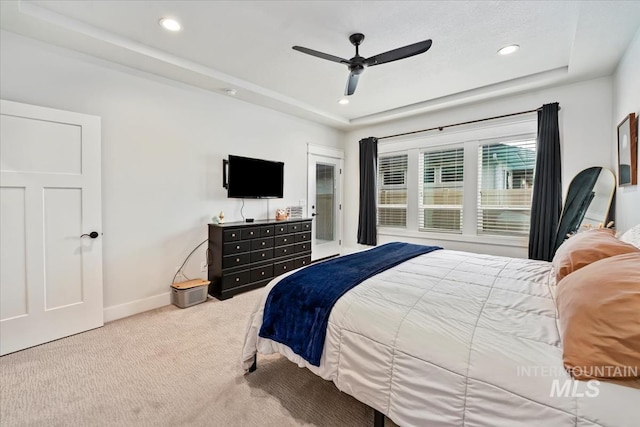 carpeted bedroom featuring ceiling fan and a tray ceiling