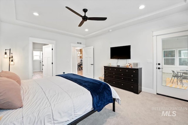 bedroom with a raised ceiling, light carpet, and ceiling fan