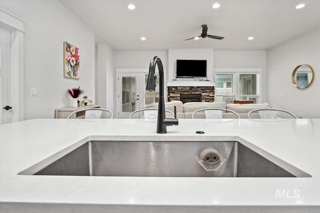 kitchen featuring ceiling fan, a fireplace, and sink