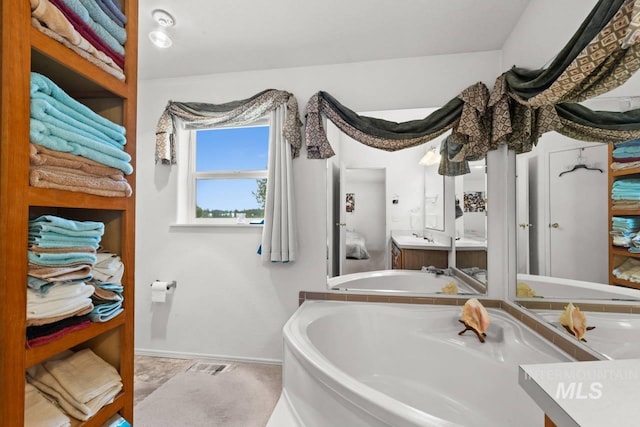 full bath featuring vanity, baseboards, and a bath