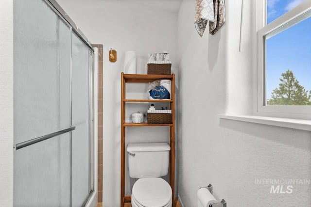 bathroom with toilet and a shower with door