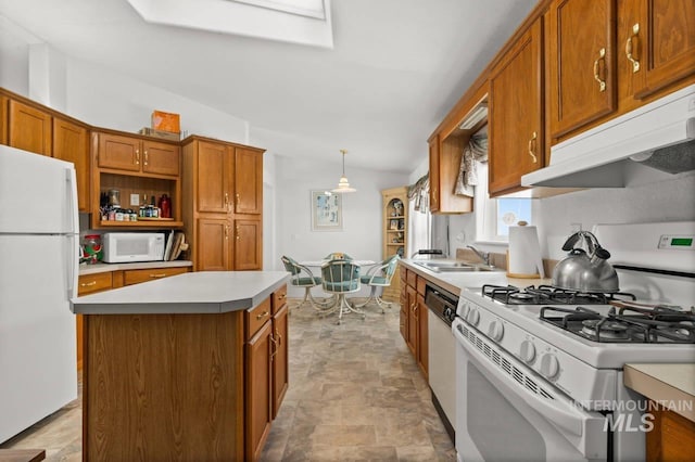 kitchen with under cabinet range hood, white appliances, a kitchen island, a sink, and brown cabinets