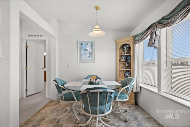 carpeted dining space with vaulted ceiling, breakfast area, visible vents, and baseboards